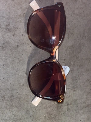 Prada solglasögon brun/beige - Snygga solglasögon från Prada med stora, runda bågar i brunmelerad plast och ljusbeige skalmar. Glasen är mörka och ger en cool retrovibe. Perfekta för att lyfta vilken outfit som helst. Kom priv och vid snabb affär kan jag ändra pris också så tveka inte på att slide in allt är äkta btw 🔥🔥