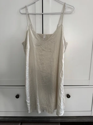 Beige nattlinne från Bodyflirt - Ett stilrent nattlinne i beige från Bodyflirt med smala, justerbara axelband och v-ringning. Materialet är mjukt och lätt, perfekt för att chilla hemma eller sova bekvämt. Enkel design som känns både modern och avslappnad.
