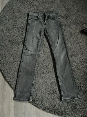 Gråa slim fit jeans från J.Lindeberg - Snygga gråa slim fit jeans från J.Lindeberg med klassisk femficksmodell och dragkedjegylf. Jeansen har en tvättad look och är tillverkade i ett mjukt denimtyg som ger en skön passform.