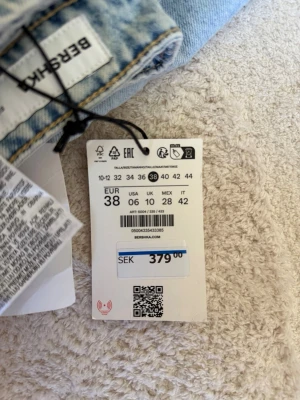 Ljusblå raka jeans från Bershka - Säljer ett par ljusblå jeans från Bershka i storlek 38. Jeansen har raka ben, klassisk femficksmodell och hög midja. Tillverkade i denim med en snygg tvättad look och detaljerade sömmar. Perfekta för en avslappnad och trendig stil.