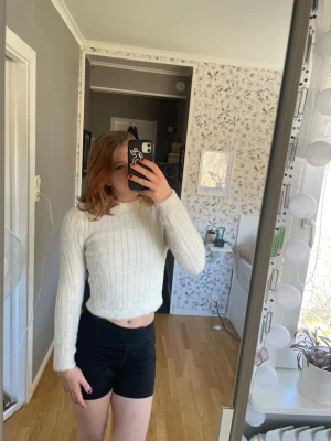 Vit stickad tröja - Säljer en vit stickad tröja med rund hals och långa ärmar. Tröjan har ett ribbat mönster och är gjord i ett mjukt material som känns skönt mot huden. Är för liten o kort för mig 