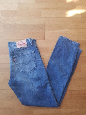 Levi's 511  - Säljer ett par klassiska blå Levi's 511 jeans i slim fit-modell. Jeansen har fem fickor, normalhög midja och är tillverkade i bomull med lite stretch. Snygg tvätt och ikonisk röd Levi's-tag på bakfickan. Perfekta för en avslappnad och stilren look.