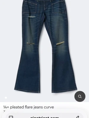 Blå utsvängda jeans med slitningar - Snygga blå jeans med utsvängda ben och slitna detaljer på låren. Jeansen har stora framfickor och en klassisk femficksdesign. Perfekta för dig som gillar retrostil och vill sticka ut med en cool look.