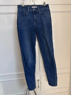 Levi's blå slim fit jeans - Säljer ett par klassiska blå jeans från Levi's i slim fit-modell. Det har blivit trändigt att ha skinny jeans i cowboy booths!!. Jeansen har fem fickor, normal midja och raka ben. Tillverkade i denim med snygg tvätt och ikoniska bakfickor med söm. Perfekta till din vardagsstil eller fest! Går även att sy om till bootcut om man vill det! 💕