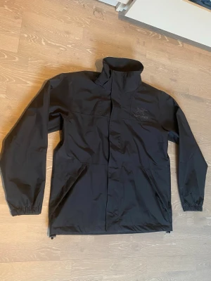 Svart regnjacka från Arc'teryx - Säljer en svart Arc’teryx skaljacka i väldigt fint skick. Stilren och funktionell design som passar både till vardag och outdoor. Jackan är lätt och smidig samtidigt som den skyddar bra mot vind och regn.  Den är i bra skick utan större slitningar, men det finns en trasig knapp (se bild 7), vilket inte påverkar funktionen särskilt mycket. Alla dragkedjor och övriga detaljer fungerar som de ska. Priset kan diskuteras och skickas inom 24 Tim 😊💨💨