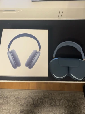 Blå Apple AirPods Max hörlurar - Snygga blå Apple AirPods Max over-ear hörlurar med stilren design. Tillverkade i aluminium och mjukt mesh-material för komfort. Levereras med matchande smart case och originalförpackning. Perfekta för musik, gaming eller film.