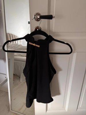 Topp med gulddetalj - Svart topp med cut-out och gulddetalj. Storlek XS. Aldrig använd. 