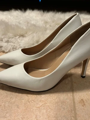 Vita klackskor, storlek 36 - Vita classy klackskor med spetsig, stängd-tå från Ellos. Perfekta till jobb, fest eller vardag. Endast testade inomhus, nyskick. Storlek 36.