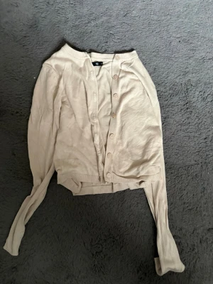 Beige kofta från lager 157, XS - Ljusbeige kofta från lager 157 i storlek XS. Koftan har långa ärmar, ribbade muddar och knäppning framtill med matchande knappar. Perfekt att slänga över en t-shirt för en enkel och stilren look.❤️