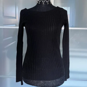 Svart ribbstickad tröja Hennes - Säljer en svart ribbstickad tröja från Hennes. Tröjan har lång ärm, rund halsringning och är figurnära i modellen. Perfekt basplagg till garderoben och enkel att matcha med olika stilar.