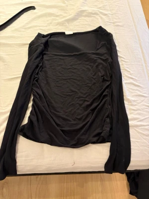 Svart långärmad topp - En svart långarmad tröja med urigning. På sidan är det lite skrunch. Använd 1 gång