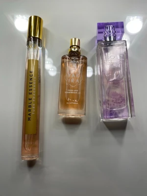 Tre parfymer i olika designer - Säljer tre parfymer: Marble Essence i smal cylinderflaska med guldlock, Zara Candy Land i beige/guld rektangulär flaska och Escada i lila transparent flaska med lila lock. 
