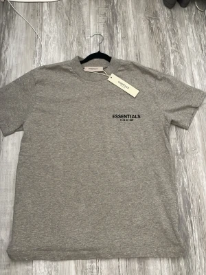 Essentials T-shirt - Säljer en helt ny Essentials t-shirt i färgen Grey Heather. Aldrig använd och alla originaltags sitter kvar. Stilren logga på bröstet och den klassiska gummiloggan i nacken. Väldigt hög kvalitet på tyget (heavyweight cotton). Storlek XS/S 