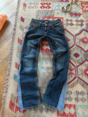Blåa bootcut jeans från True Religion  - Säljer ett par av mina favoritjeans som tyvärr blivit försmå.🥲 Jag har själv sytt dem bootcut och lågmidjade och den enda bilden ja kunde hitta med hur de sitter är den sista. De har inga tydliga defekter förutom lite heelbite.  Mått:  Rakt över midjan: 38cm Innerbenslängd: 84cm Längd: 102cm Skrev: 17cm