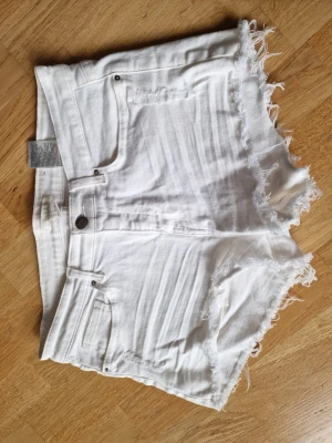 Vita jeansshorts med fransig kant - Snygga vita jeansshorts med fransig och rå kant nertill.🌸Kommer från djur och rökfritt hem 🌸Inköpt på H&M 🌸Inga fläckar dock någon nyansskillnad på insidan som man kan ana på etikettbilden samt liten minitråd/tygboll om man är petig som syns på sista bilden.