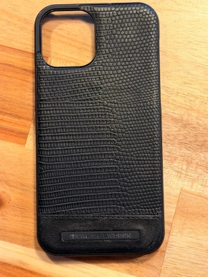 Svart mobilskal iPhone 12 Pro - Snyggt svart mobilskal från iDeal of Sweden med stilrent ormmönster i konstläder. Skalet har en matt finish och är designat för att passa perfekt runt kameran. Ger mobilen en exklusiv look och bra grepp.