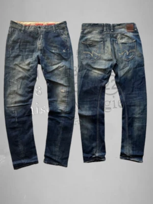 Blå slitna archive jeans - Jättesnygga jeans i storlek 29. Skön design på bakre fickorna. Lite slitningar och tvättningar. Midjemått=41cm. Total längd = 105cm. Snabb frakt.