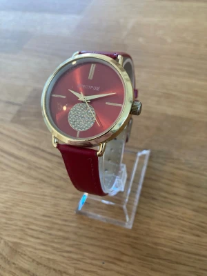 Spectrum Gold 38mm Damklocka - Säljer en Spectrum Gold damklocka med ett rött läderarmband. Klockan har ett guldpläterat boett och en röd urtavla med strassdetaljer. Baksidan av boetten är i rostfritt stål. Klockan är i fint skick enligt bilder. Behöver nytt batteri.   Nypris: 1200 SEK Mitt pris: 389 SEK  Skickas alltid snabbt och spårbart. Skriv vid frågor och se gärna mina andra annonser! 
