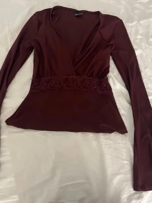 Vinrött nattlinne med spets Gina Tricot - Använt cirka två gånger för jag tröttnade. Vinröd blus  från Gina Tricot i mjukt och stretchigt material. Blusen har en dekorativ spetskant med blommönster framtill som ger en romantisk känsla. Perfekt för dig som gillar feminina detaljer och en bekväm stil.