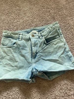 Ljusblåa denimshorts - Snygga ljusblåa shorts i denim med klassisk femficksdesign och råa kanter nertill. De har normal passform och stängs med knapp och dragkedja. 