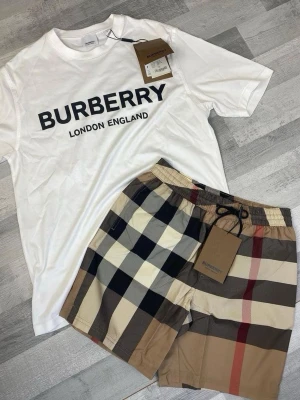 Rutiga shorts från Burberry - Säljer ett par klassiska rutiga shorts från Burberry med elastisk midja och snörning. Shortsen har det ikoniska Burberry-mönstret i beige, svart, rött och vitt. Perfekta för sommaren och tillverkade i ett lätt och bekvämt material.