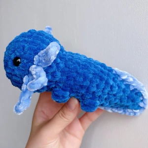 Virkad blå axolotl - Blå virkad axolotl – handgjord & unik💙🧶 Superfin, mjuk och söt liten axolotl i blå, perfekt som present eller för att ge lite extra charm till hyllan, soffan eller skrivbordet! 	•	Handgjord med kärlek 💙 	•	Virkad i mjukt garn 	•	Ca 17-18cm lång 	•	Unik – bara ett exemplar!  ✨ Pris: 150 kr ✨  Passar både som prydnad och kramdjur 🧸OBS! Dessa innehåller säkerhetsögon som ej är rekommenderade för barn under 3 år!