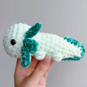 Virkad grön axolotl - Grön virkad axolotl – handgjord & unik💚🧶 Superfin, mjuk och söt liten axolotl i grön, perfekt som present eller för att ge lite extra charm till hyllan, soffan eller skrivbordet! 	•	Handgjord med kärlek 💚 	•	Virkad i mjukt garn 	•	Ca 17-18cm lång 	•	Unik – bara ett exemplar!  ✨ Pris: 150 kr ✨  Passar både som prydnad och kramdjur 🧸OBS! Dessa innehåller säkerhetsögon som ej är rekommenderade för barn under 3 år!