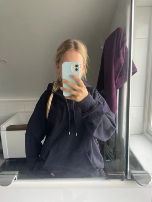 Svart oversized hoodie med huva - En svart oversized hoodie med huva och dragsnören. Hoodien har en stor magficka framtill och ribbade muddar vid ärmslut och nederkant. Perfekt för en avslappnad och chill stil.