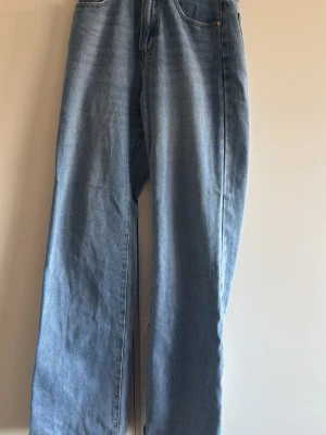 Ljusblåa raka jeans i loose fit high waist - Säljer ett par ljusblå jeans med rak och loose passform. Jeansen har klassisk femficksdesign och hög midja. Tillverkade i denim med en lätt tvättad look. Perfekta för en avslappnad och trendig stil.