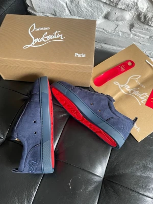 Blåa Christian Louboutin sneakers - Snygga mörkblå sneakers från Christian Louboutin i mocka med ikoniska röda sulor. Helt nya loubs HELT OANVÄNDA aldrig använda. Storlek 43 finns. Alla tillbehör medföljer och OG. OBS TAR SLUT SNABBT. Pris kan diskuteras vid snabb affär 