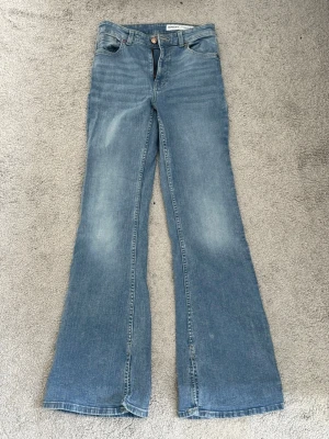 Blå utsvängda jeans från Bershka - Snygga ljusblå jeans från Bershka med utsvängda ben och klassisk femficksmodell. Jeansen har hög midja och är tillverkade i bomullsdenim med lätt tvättad look. Perfekta för en trendig och avslappnad stil.