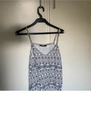 Mönstrad linnetopp med tunna axelband - Säljer en snygg linnetopp med tunna axelband och v-ringning. Toppen har ett detaljerat mönster i blått, rött och vitt och är perfekt för varma dagar. Lätt och luftig känsla, passar till jeans eller kjol.