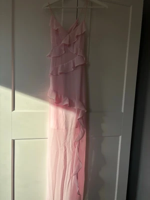 Ljusrosa långklänning med volanger - SÄLJER ÄVEN PÅ VINTED-SKRIV FÖRSTSuperfin ljusrosa långklänning med tunna axelband och volangdetaljer framtill. Klänningen har omlottkänsla upptill och är gjord i ett lätt, flowy material som ger en romantisk vibe. Perfekt för sommarens alla tillfällen!