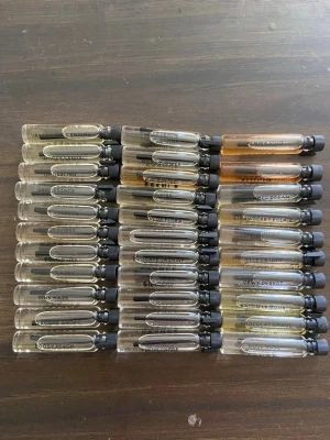 Parfymprover mixade dofter - Säljer ett set med 30 parfymprover i små glasflaskor med svart skruvkork. Dofterna har namn som Irresistible Enigma, Woody Sandal, Lady Essence och Pink Haze. Färgerna varierar från klara till ljusgula och bärnstensfärgade toner. Perfekt för dig som vill testa olika parfymer.