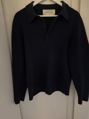 Mörkblå kragtröja från A Day's March - Mörkblå tröja från A Day's March med klassisk krage och knäppning framtill. Tröjan har lång ärm och en stilren, enkel design som passar perfekt till jeans eller chinos. Storlek S. Mycket bra skick. 