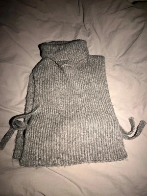 Grå stickad väst med snörning - Säljer en grå ribbad stickad väst med polokrage och snörning i sidorna. Det finns tyvärr inget märke på den men den är i storlek S/M!!🥰