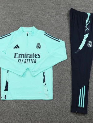 Real Madrid träningsset Adidas blå- M i junior  - Snyggt träningsset från Adidas för Real Madrid, med ljusblå långärmad tröja och mörkblå byxor. Tröjan har halv dragkedja, klubbmärke och Adidas-logga samt texten 'Emirates Fly Better' på bröstet. Byxorna har matchande detaljer och klubbmärke. Perfekt för fotbollsträning.