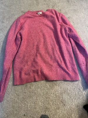 Rosa stickad tröja med rund hals - Mysig rosa stickad tröja med rund hals och långa ärmar. Tröjan har ribbstickade muddar vid ärmslut och nederkant. Perfekt för kyliga dagar och enkel att matcha med jeans eller kjol.