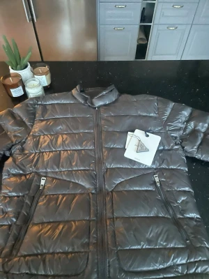 Svart dunjacka från Moncler - Snygg svart dunjacka från Moncler med glansig finish och raka sömmar. Jackan har två dragkedjeförsedda fickor framtill, hög krage och klassisk Moncler-logga på ärmen. Perfekt för kalla vinterdagar och riktigt stilren look. Dragkedjan är lite isönder men går att fixat lätt som ni får med i ert köp. Vid frågor dm mig ! 