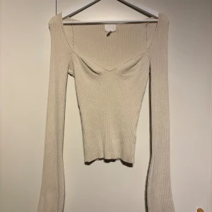 Beige ribbad långärmad topp - Säljer en beige ribbad topp med lång ärm och snygg v-ringad hals. Aldrig använd 