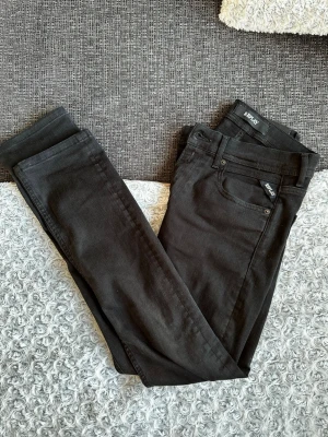 Svarta Replay jeans - Snygga svarta skinny jeans från Replay med klassisk femficksdesign och diskret logga på fickan. Jeansen har smal passform och är tillverkade i stretchigt material för extra komfort. Perfekta för dig som gillar en stilren och modern look.