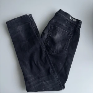 Dondup jeans - Snygga svarta jeans från Dondup med coola slitningar och blekta detaljer. Modellen har klassisk femficksdesign, raka ben och en diskret logga på bakfickan. Jeansen är tillverkade i mjukt denimtyg som sitter skönt hela dagen. Väldigt unika 