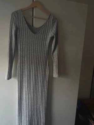 Grå ribbad långärmad klänning - Snygg grå ribbad klänning med lång ärm och v-ringad hals. Klänningen är figurnära och har en stilren, enkel design som passar perfekt till många olika looks. Materialet känns mjukt och stretchigt för en bekväm passform. För fler bilder/information skriv gärna, priset kan justeras 🤗❤️