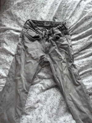 Grå jeans från 157 med utsvängda ben - Säljer ett par grå jeans från 157 med klassisk femficksmodell och utsvängda ben. Jeansen har tydliga sömmar och bälteshällor, samt en snygg tvättad look. Perfekta för dig som gillar en avslappnad och stilren vibe. Fräscha ner mot fötterna