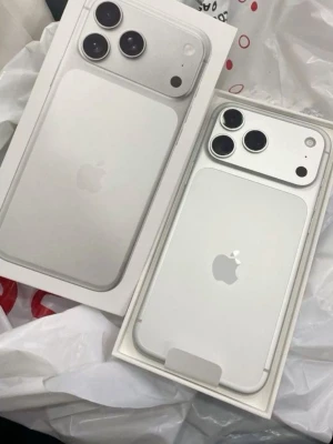 Iphone 17 pro max 512 GB - Snygg vit iPhone 17 PRO max med stilren design och två stora kameralinser på baksidan. Mobilen har en slimmad form, rundade hörn och den klassiska Apple-loggan i mitten. Tillverkad i glas och metall för en premiumkänsla. Perfekt för dig som gillar modern teknik och clean look.