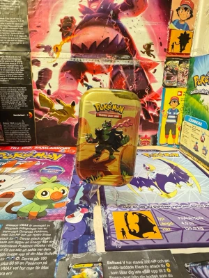 Pokémon TCG: Scarlet & Violet ShroudedFable Mini Tin (Okidogi) - Pokémon TCG: Scarlet & Violet—Shrouded Fable Mini Tin (Okidogi) Pokémon-favoriter i din handflata! Ta din samling till nästa nivå med denna exklusiva Mini Tin med den mystiska Pokémon Okidogi. Perfekt storlek för att ta med dina favoritkort överallt! Innehåll i denna Mini Tin: • 2 Pokémon TCG: Scarlet & Violet—Shrouded Fable boosterpaket. • 1 klistermärkesark. • 1 Pokémon-art kort som visar motivet från denna Mini Tin - samla alla 5 i serien för att färdigställa bilden! Varför välja Shrouded Fab