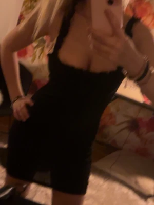 Svart tight kortklänning - Snygg svart tight kortklänning med breda axelband och fyrkantig urringning. Klänningen har en kroppsnära passform och är perfekt för dig som gillar en stilren och enkel look. Materialet ser ut att vara stretchigt och bekvämt.