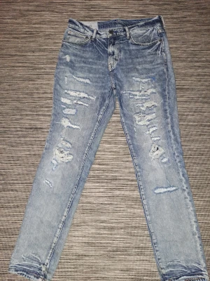 Ljusblå slitna skinny jeans - Säljer ett par ljusblå skinny jeans med rejält slitna detaljer och hål på framsidan. Jeansen har klassisk femficksmodell, normal midja och dragkedja med knapp. Perfekta för en avslappnad och trendig look.