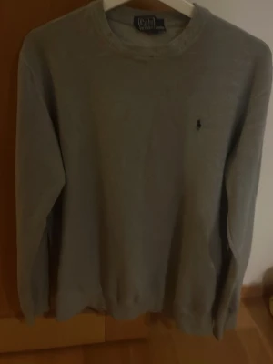 Grå sweatshirt från Polo Ralph Lauren - Klassisk grå sweatshirt från Polo Ralph Lauren med rund halsringning och den ikoniska lilla broderade loggan på bröstet. Perfekt basic att ha i garderoben och enkel att matcha med allt. Passar som L