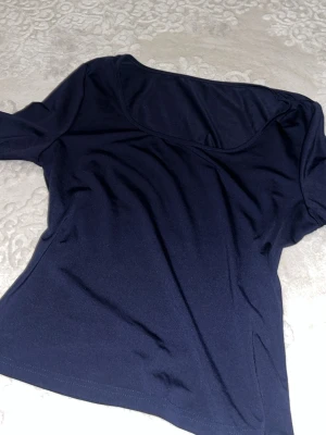 Mörkblå långärmad topp - En enkel och stilren mörkblå långärmad topp med rund halsringning. Tillverkad i ett mjukt och stretchigt material som sitter bekvämt på kroppen. Perfekt att matcha med jeans eller kjol för en clean look.